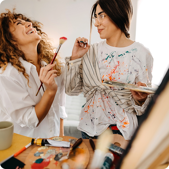 Two women painting and laughing together