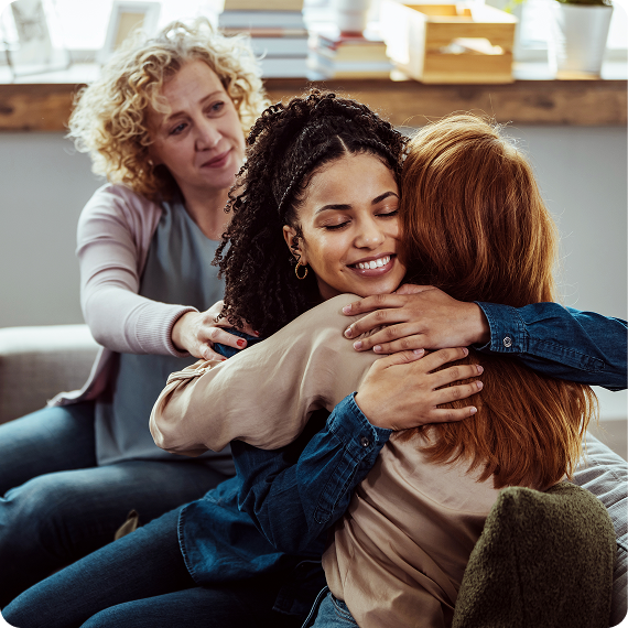 Three women hugging, friend offering support